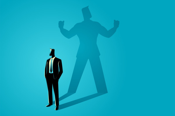 A suited figure stands before an oversized shadow flexing both arms